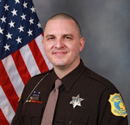 A photo of Deputy Proxmire with an American flag in the background.